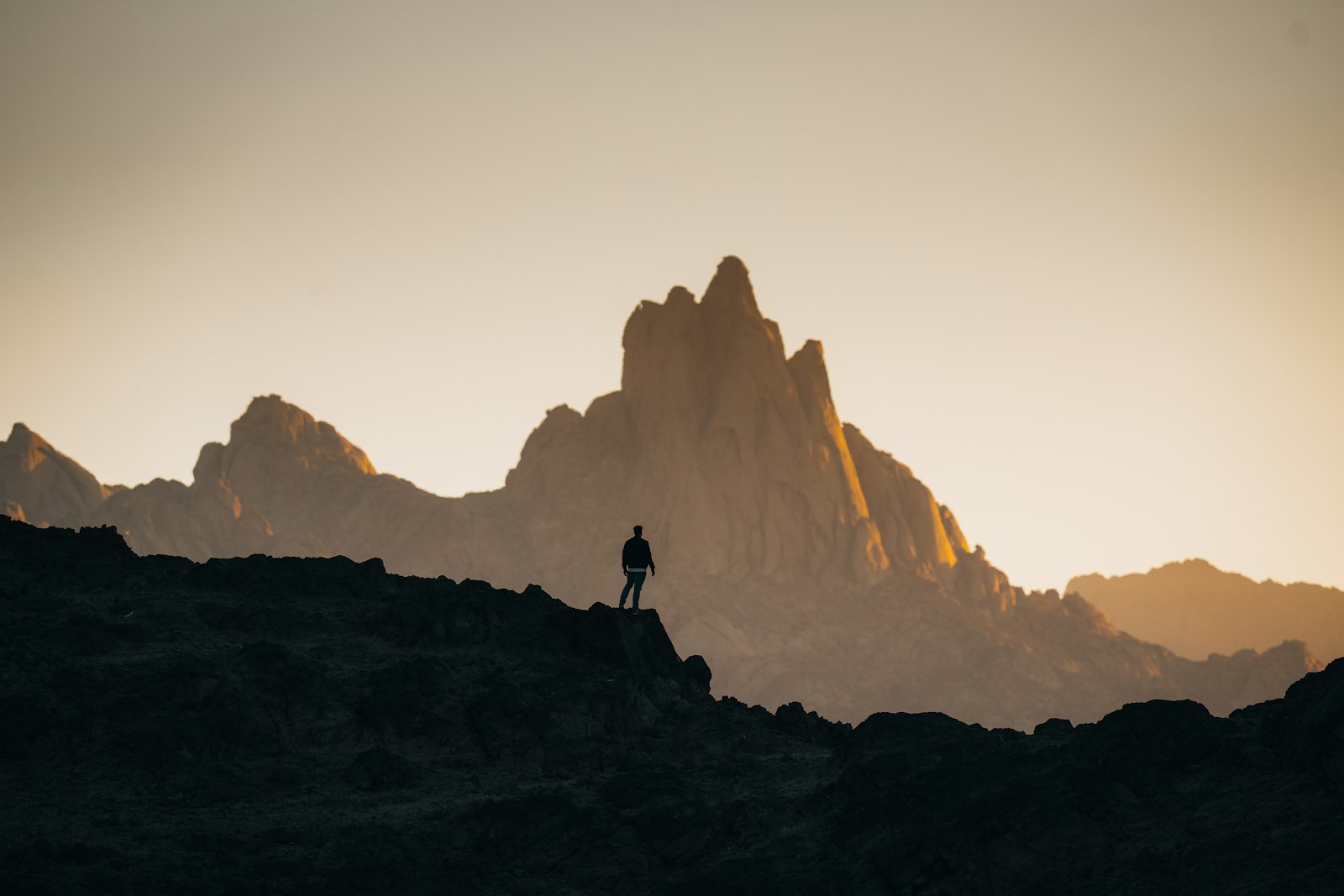 Viajero en silueta frente a un macizo de montañas al amanecer