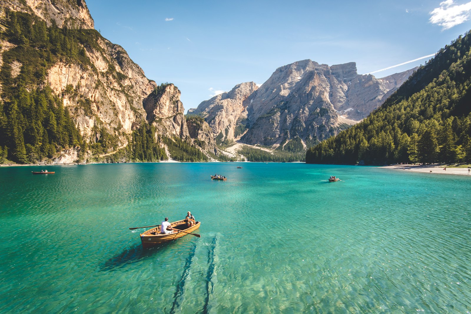 Barca de remos sobre un lago alpino de aguas turquesa rodeado de montañas